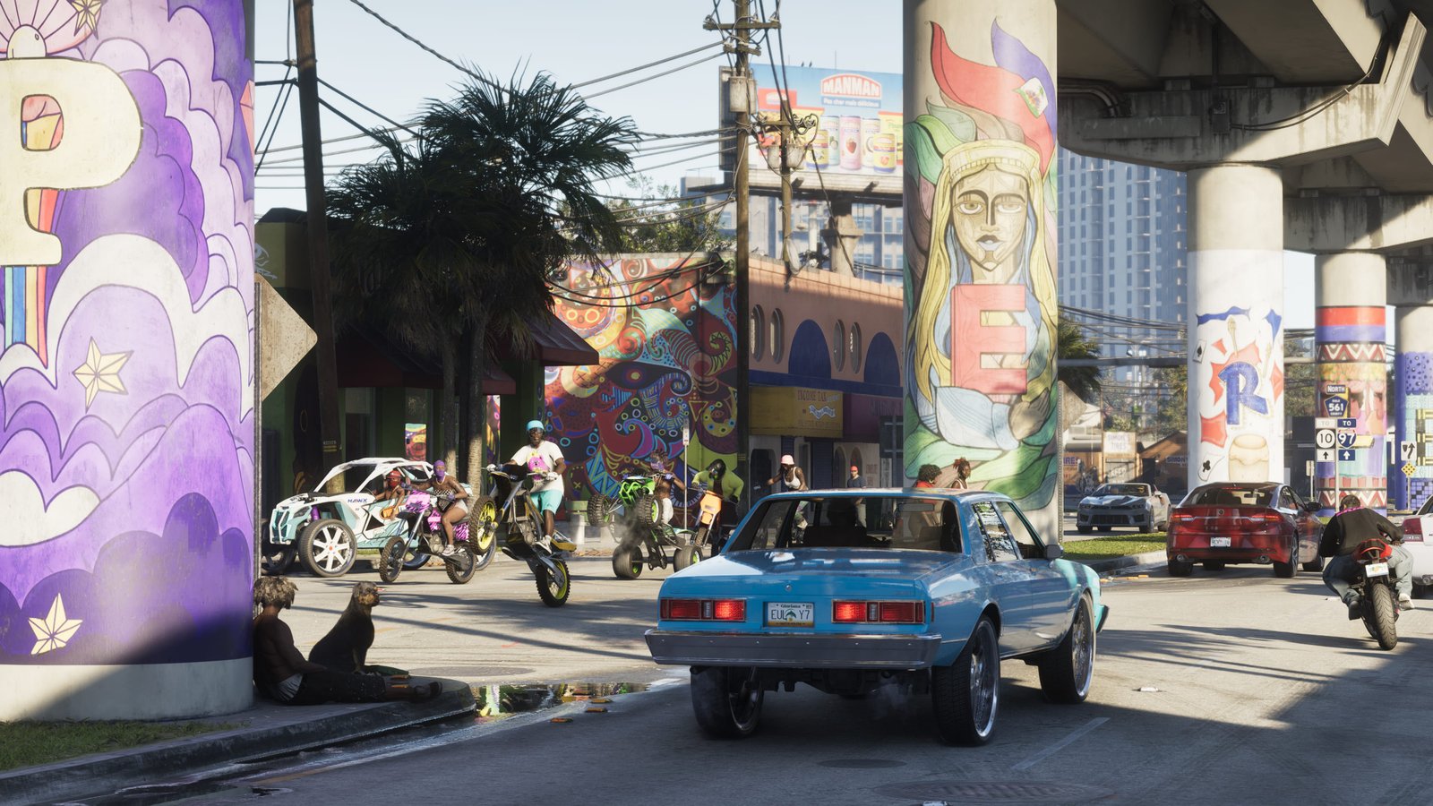 Rua colorida de Vice City com murais nos pilares, carros, motos e pessoas em uma área urbana ensolarada.